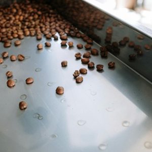 Detailed close-up of coffee beans cooling in a stainless steel roasting machine indoors.