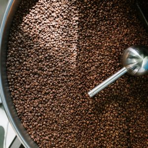 Top view of freshly roasted coffee beans in a spinning roasting machine, showcasing the process in a coffee production facility.