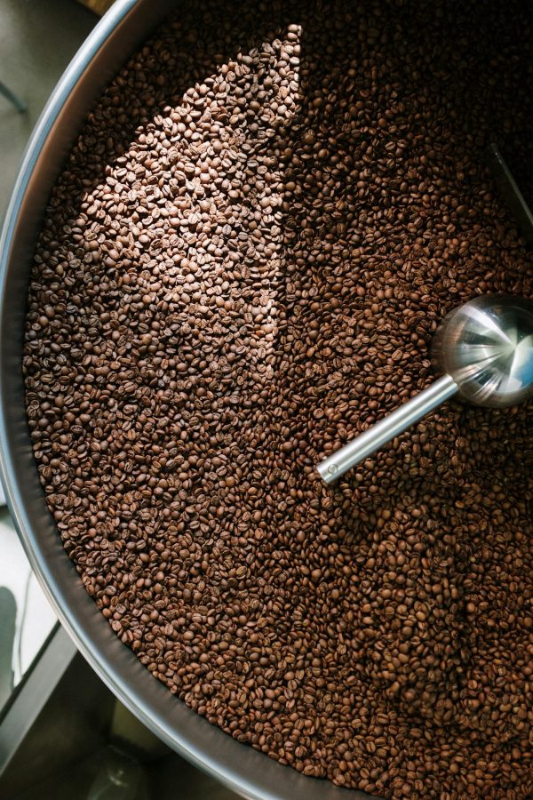 Top view of freshly roasted coffee beans in a spinning roasting machine, showcasing the process in a coffee production facility.